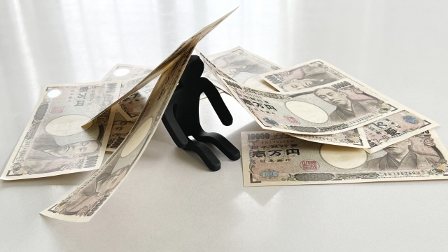 お金の上でうなだれる。宇和島市で借金返済の相談は無料でできます